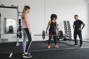 Women Deadlifting Weights with a Personal Trainer in the Gym