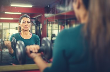 Woman doing dumbbell workout in a gym to build bigger biceps