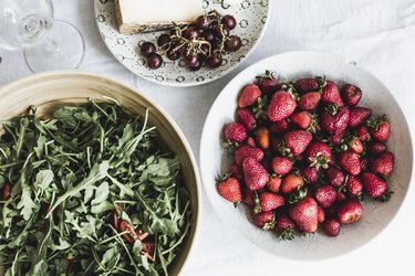 Cheese, bread, fruits and arugula on a table