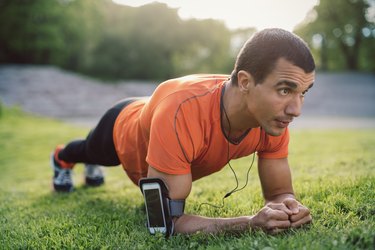 Man doing plank exercise on grassy field at park