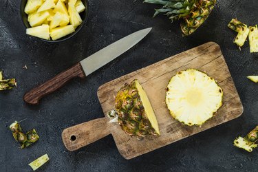 Cutting fresh pineapple and pineapple on wooden board. Top view