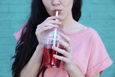 Young woman drinking soft drink, partial view