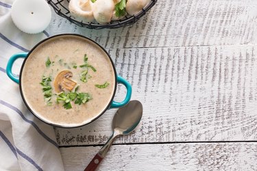 Mushroom champignon cream low carb soup on white wooden board. View from above. Space for text.