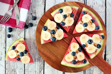 Watermelon pizza with bananas, blueberries and yogurt on serving board