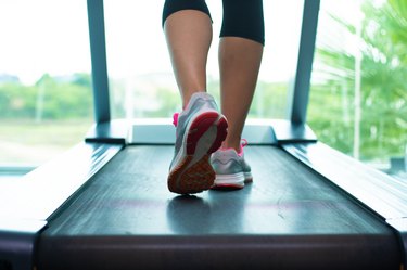 Close up womans legs in pink sneakers on a. Treadmill in the gym