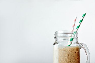 Protein cocktail with milk, vanilla in a glass jar with straws. Sports nutrition