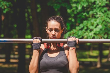 Sportswoman doing pullups in park.