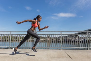 Attractive ethnic female sprinter training in the city