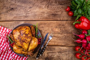 Baked chicken with herbs and vegetables for festive dinner on wooden table. Christmas, Thanksgiving Day, holidays concept. Top view