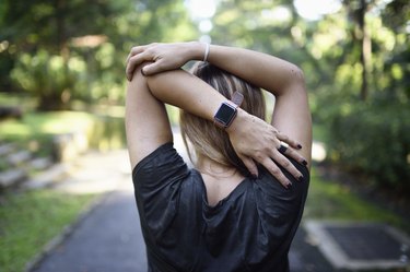 Woman stretching on a trail with a fitness tracker