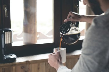 Person pouring coffee into cup at home
