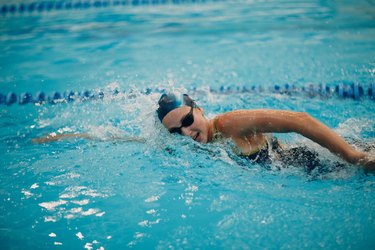 Young woman swimmer swims in swimming pool