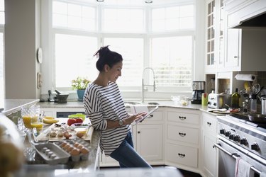 Woman using myWW app on digital tablet to prepare a recipe in kitchen