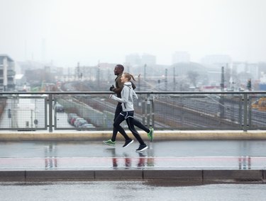 two friends jogging across urban street bridge