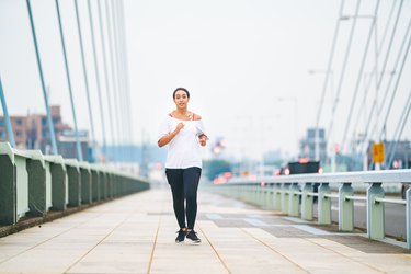 Mixed race woman running in city on cloudy bad weather day