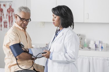 doctor taking senior patient's blood pressure