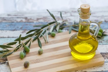 Olive oil in glass and olive on cutting board