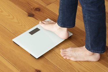 View of a person's feet stepping onto a bathroom scale