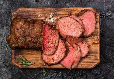 Roast beef on cutting board with salt and pepper. Top view.