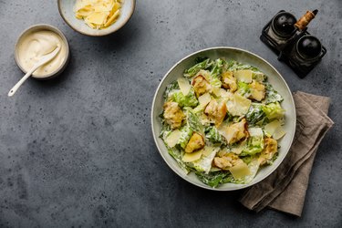 Caesar salad with croutons and parmesan cheese on concrete background copy space