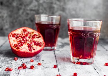 Glasses of pomegranate juice and sliced pomegranate