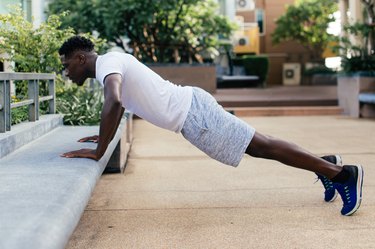 Young African American man doing push up in city park