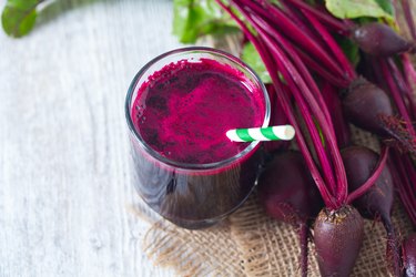 beetroot juice on wooden table next to raw beets.