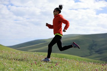 A person in a red jacket running along a grassy path