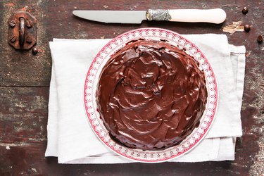 Homemade chocolate truffle brownie cake with chocolate cream spread on a plate on a wooden table. Sweet food. Easter cake.