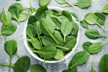 Spinach leafs in bowl on grey wooden table