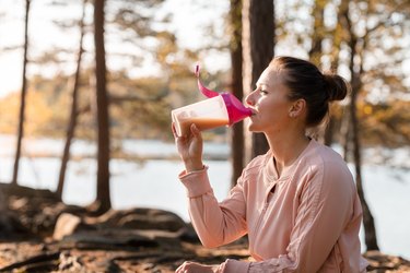 Woman drinking a plant-based protein powder shake after outdoor workout