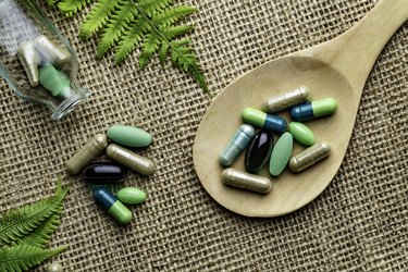 Various green pills on a wooden spoon used to get silica hair growth results and bamboo silica for hair growth reviews