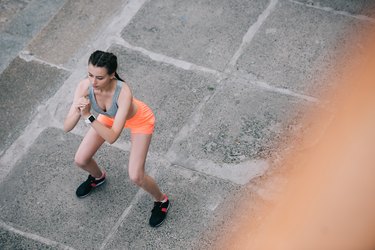 overhead view of young sportswoman squating in city