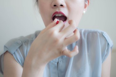 A woman is taking a medicine capsule