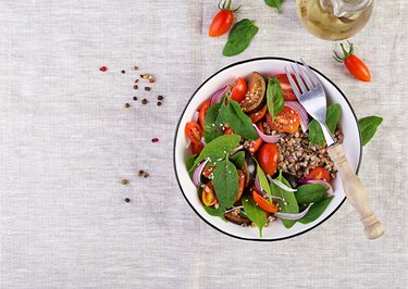 Buckwheat salad with cherry tomatoes, red onion and fresh spinach. Vegan food. Diet menu. Top view. Flat lay
