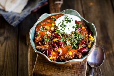 Chili con carne with kidney beans and corn, sour cream, parsley, tortilla bread