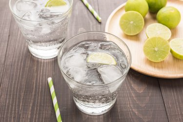 Fresh cocktail with soda, lime on a wooden background