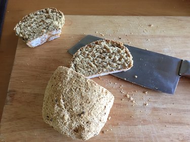 Sliced bread and knife on wooden table background.