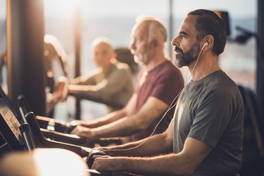 Man listening to cycling music during exercising class in a gym.