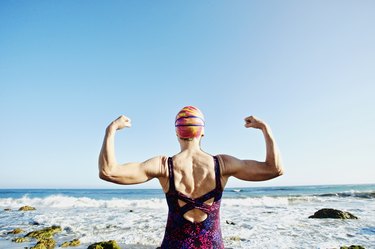 年长的白人女人炫耀她的上半身肌肉在海滩