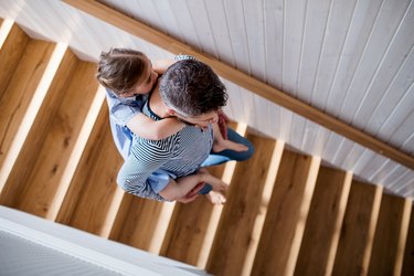 Top view of mature father and small daughter indoors at home, walking down stairs.