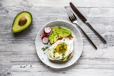 Toast with with fried egg, avocado, red radish, tomato and cress