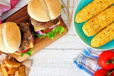 Picnic scene with hamburgers, corn and potato wedges