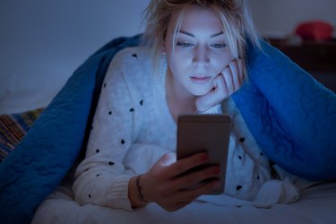 A woman reading the news anxiously as a symptom of COVID PTSD