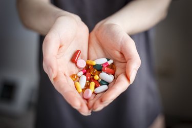 Female holds pills of different color in hand. Concept of health