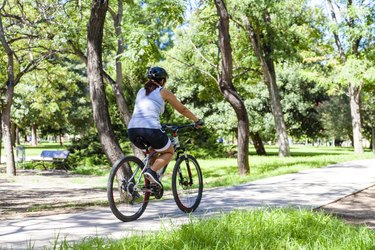 Woman riding bycicle at the park. Rear view