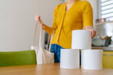 Young person taking out toilet papers from shopping bag at home