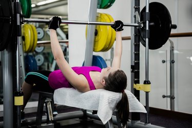 Fit woman lifting the barbell bench press