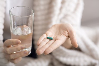 Close up of woman holding glass of water and pill