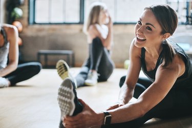 A smiling woman stretching after a workout at the gym